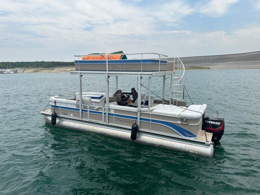 Premier pontoon boat with upper deck and spiral slide floating on the water.